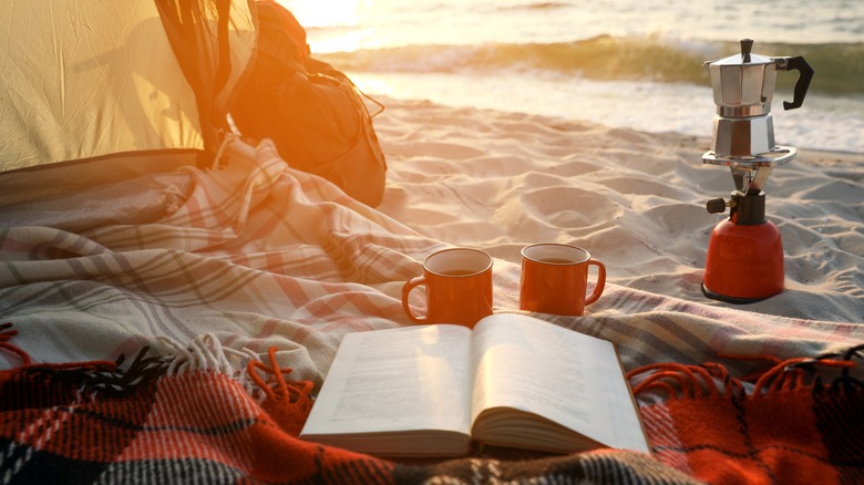 beach blanket, book, and coffee
